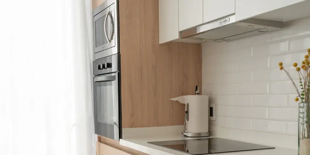 Cocina integral con torre de hornos y cubierta blanca en Querétaro — Casa Iktan