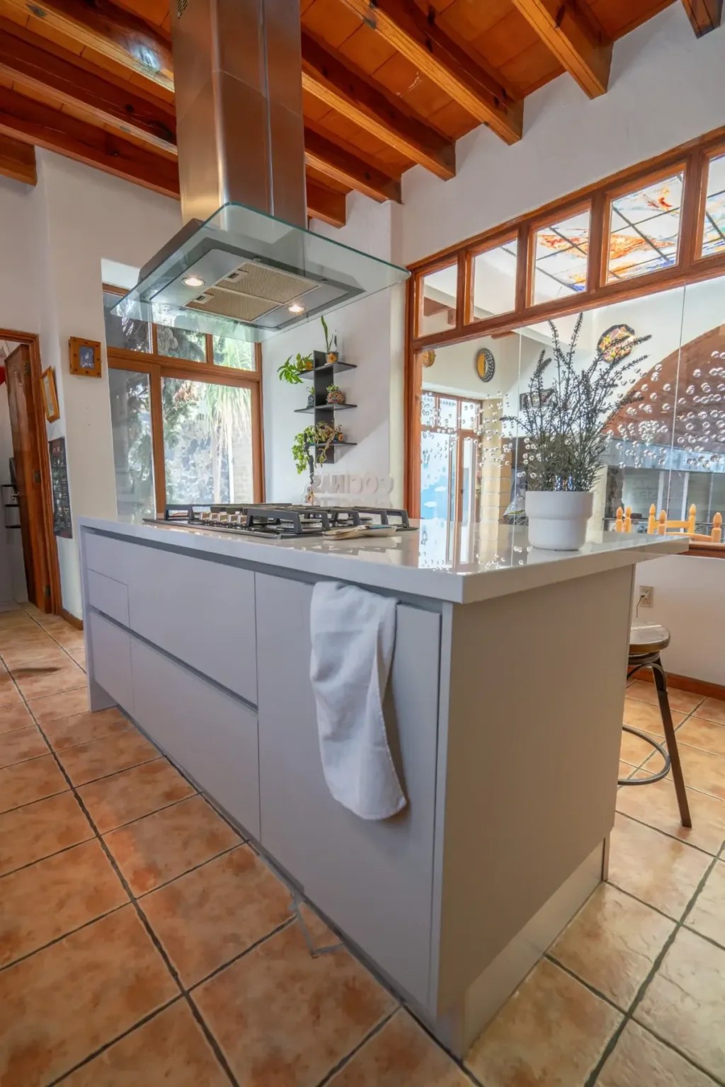 Cocina con isla Sand Ultramate, campana de vidrio y techo de madera con vigas en Juriquilla, Querétaro