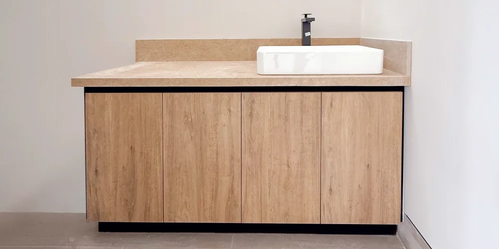 Mueble de baño tipo vanity con puertas de melamina, cubierta tipo piedra y lavabo sobre encimera con grifería negra — Casa Iktan Querétaro